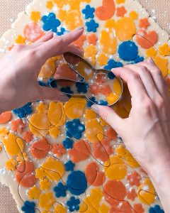 Cutting out bunny cookie from the colourful rolled butter cookie dough.